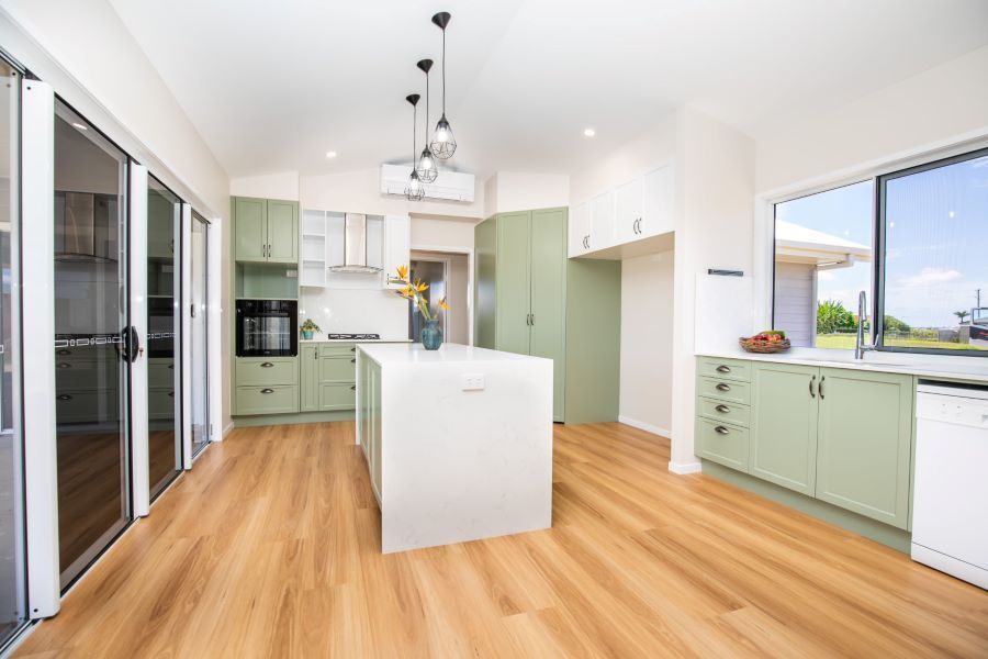 A kitchen with green cabinets and a large island in the middle.