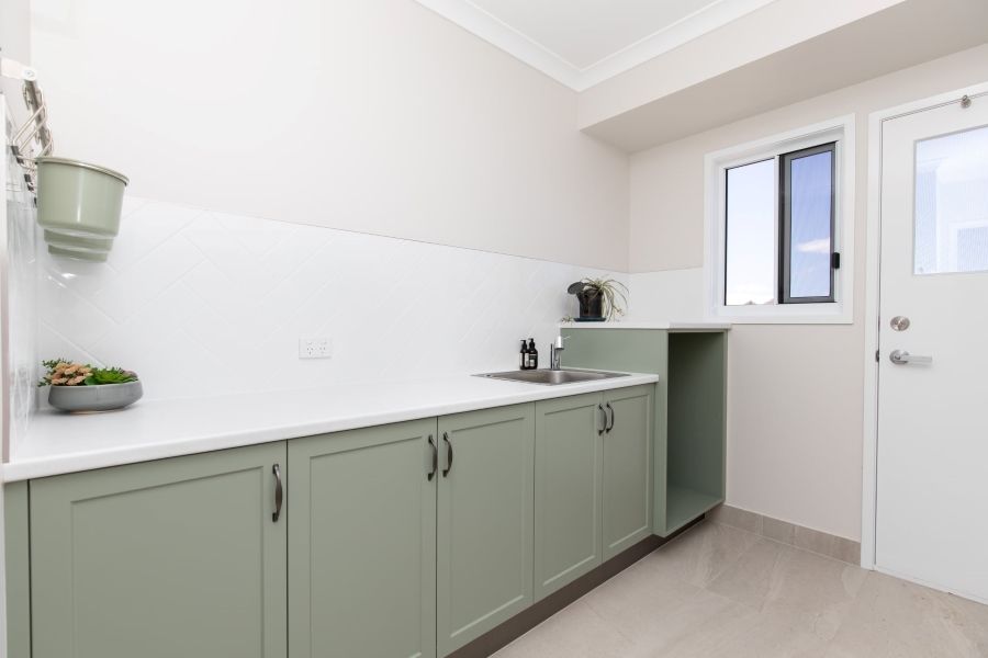 A Kitchen With Green Cabinets , a Sink , and a Window — Regalline Cabinets & Joinery in Svensson Heights, QLD