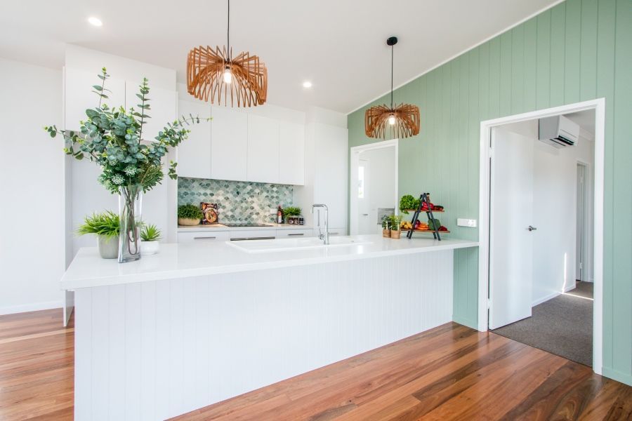 A Kitchen With White Cabinets , Wooden Floors , and Green Walls — Regalline Cabinets & Joinery in Svensson Heights, QLD