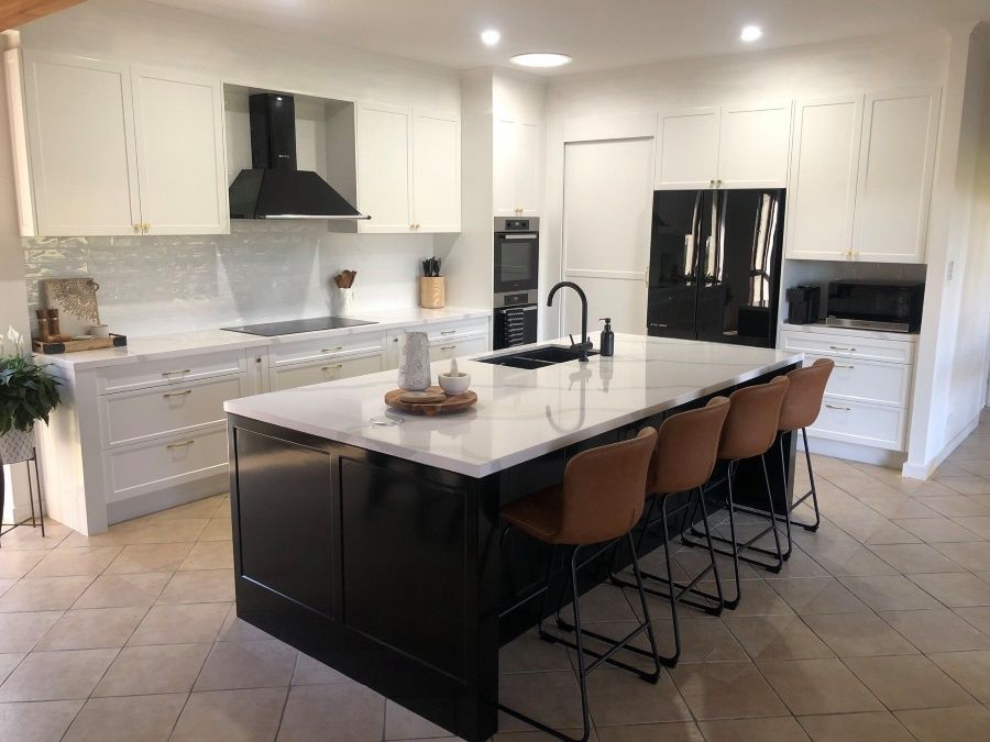 A Kitchen With White Cabinets and a Black Stove Top Oven — Regalline Cabinets & Joinery in Svensson Heights, QLD
