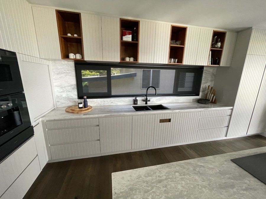A Kitchen With White Cabinets , a Sink , and a Window — Regalline Cabinets & Joinery in Svensson Heights, QLD
