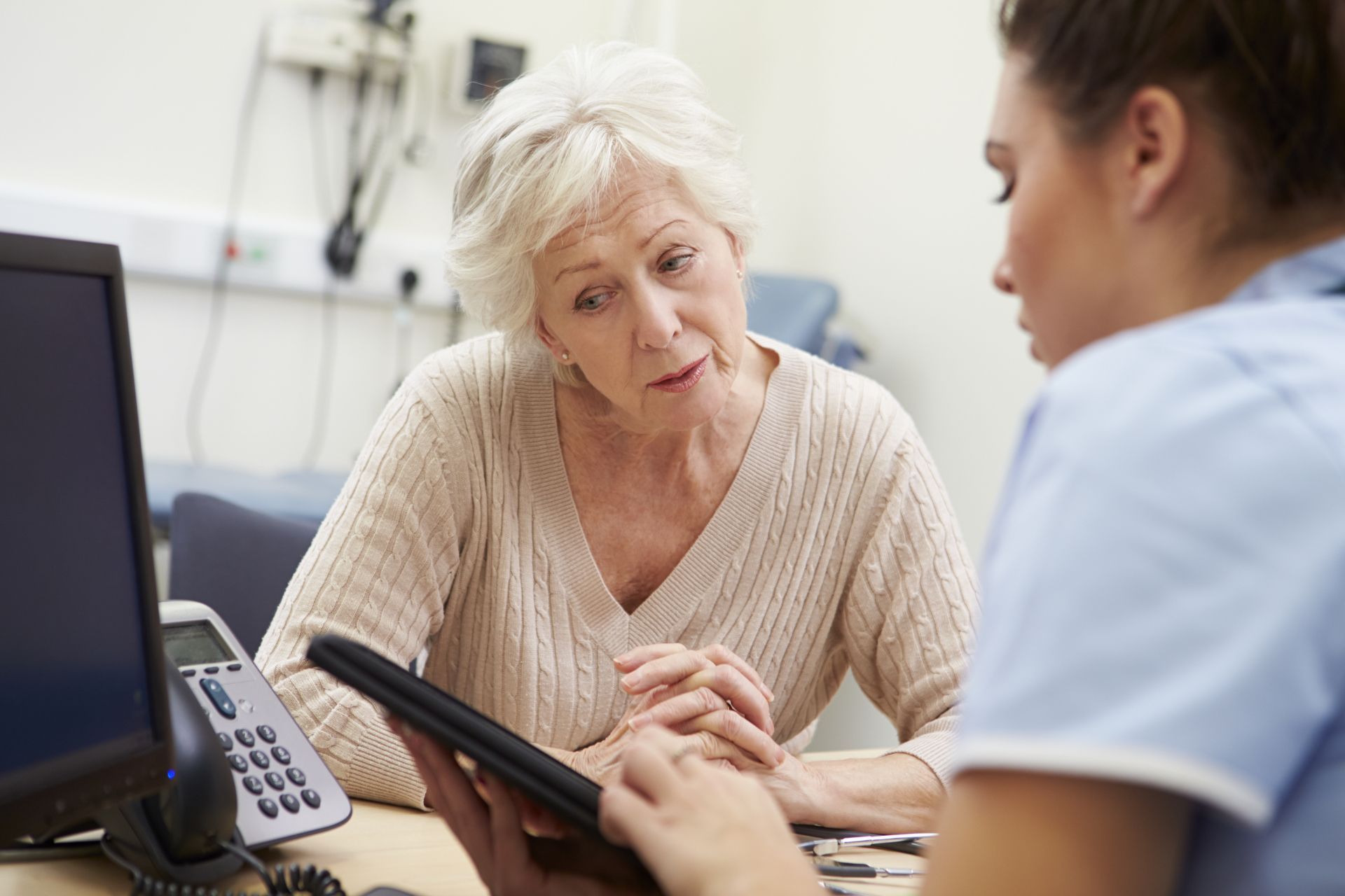 A female nurse talking to an older woman during a checkup