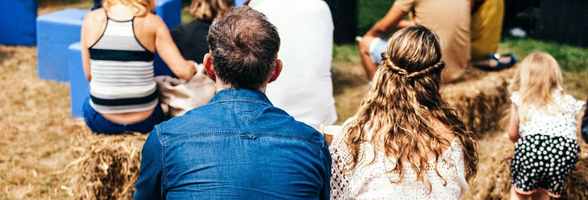 A middle-aged couple sat on hay bales while on a family day out