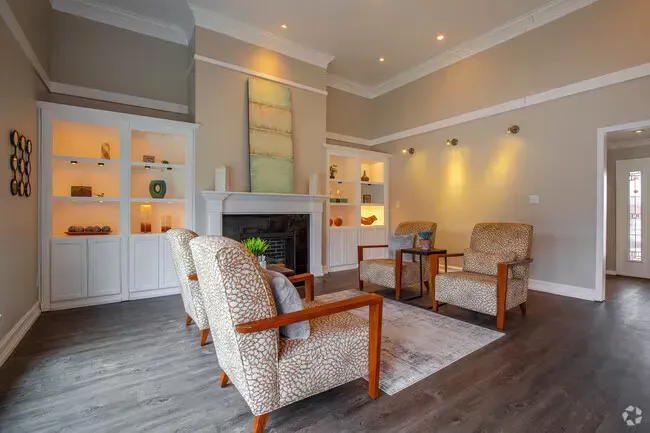 Living room with patterned chairs, white built-ins, fireplace, and gray walls.