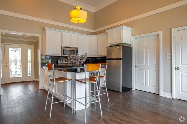 Kitchen with white cabinets, black countertop island, stainless steel appliances, and wood floors.