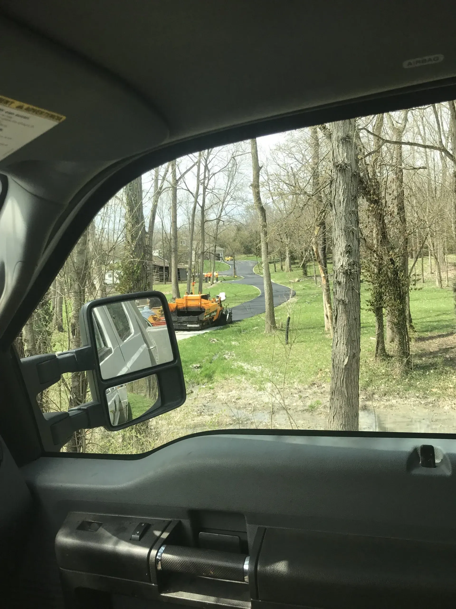 A truck is parked on the side of the road in the woods.