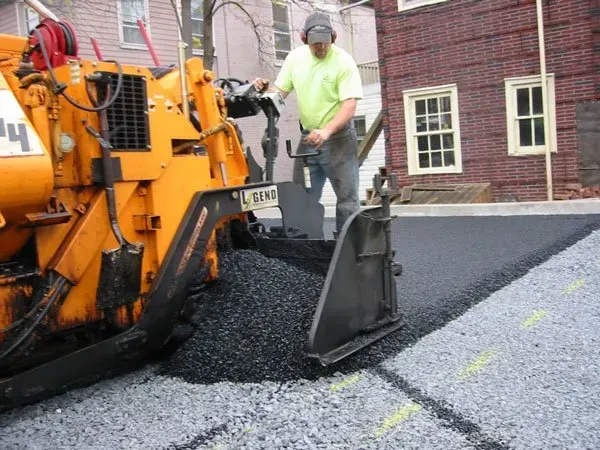 A man is working on a road with a machine that has the number 44 on it