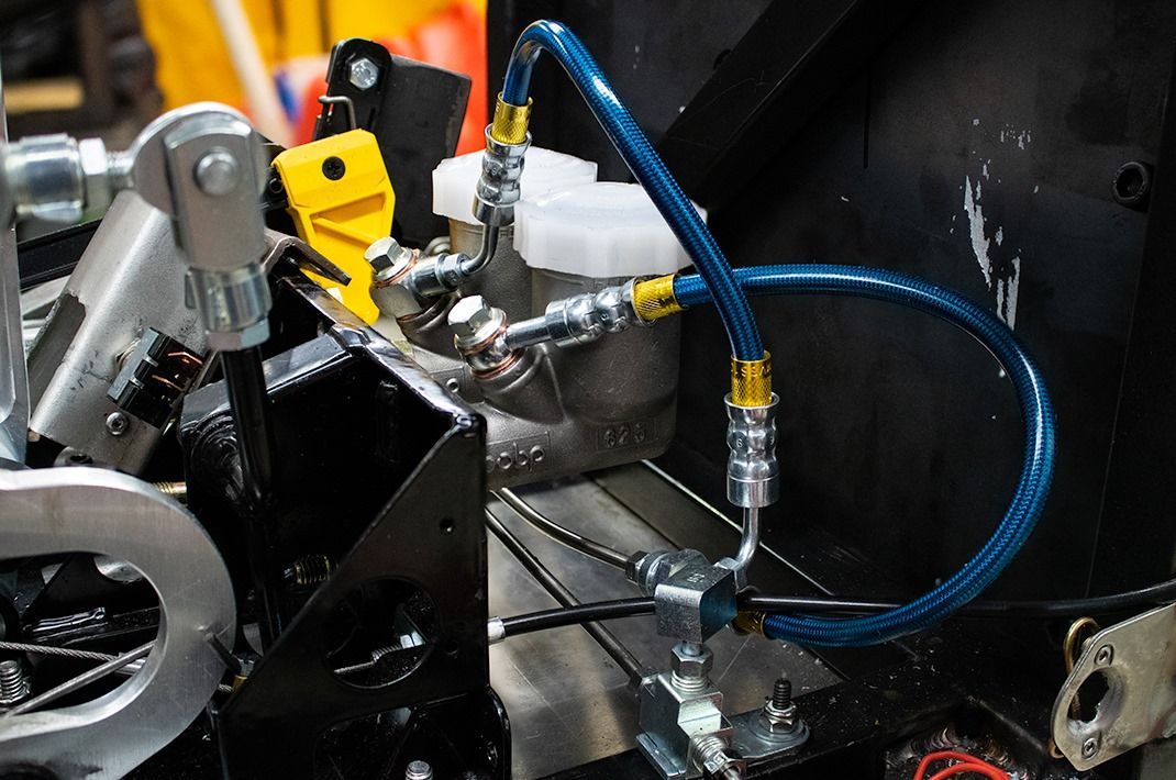 Four custom brake hoses with red/blue fittings on a workbench with tools.