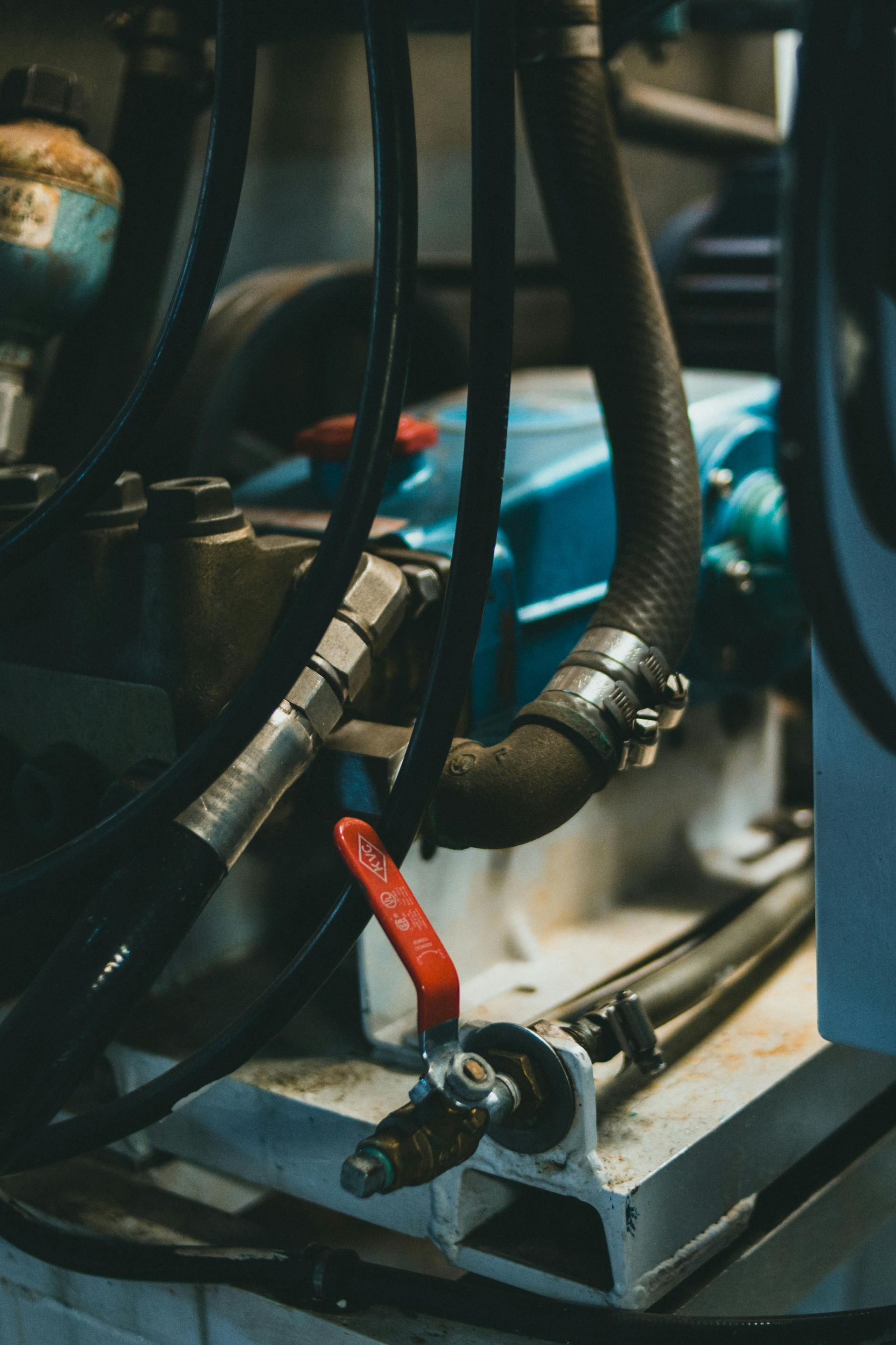 Close-up of industrial machinery with black hoses, a red valve, and metal components.