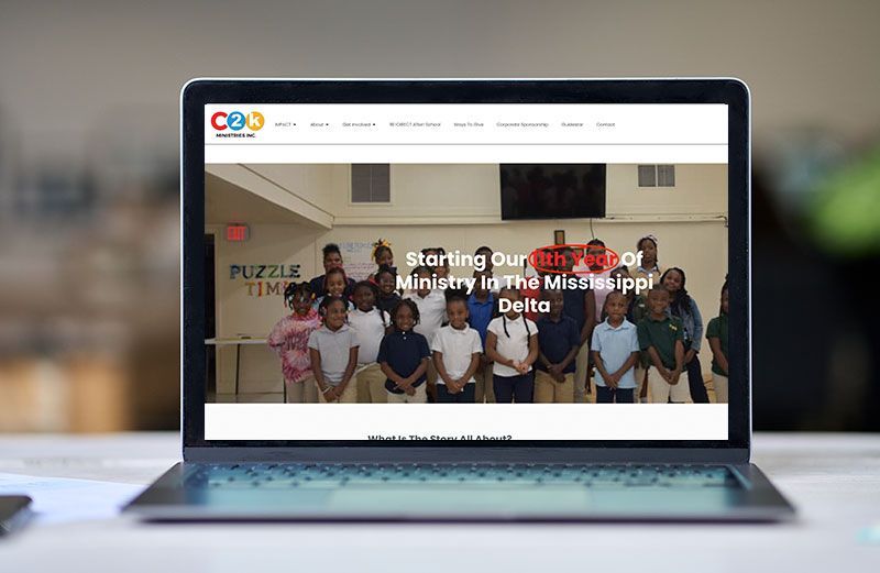 A laptop computer is sitting on a table with a group of people on the screen.