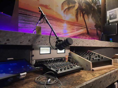 A microphone is sitting on a wooden table next to a mixer.