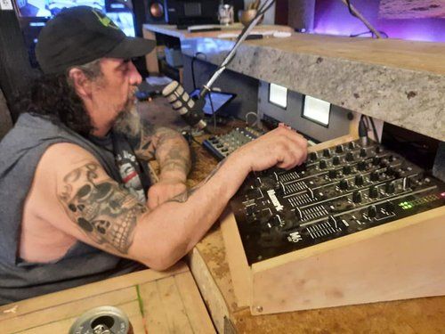 A man with a tattoo on his arm is sitting in front of a mixer.
