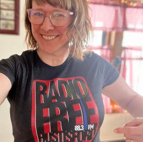 A woman wearing glasses and a radio free t-shirt