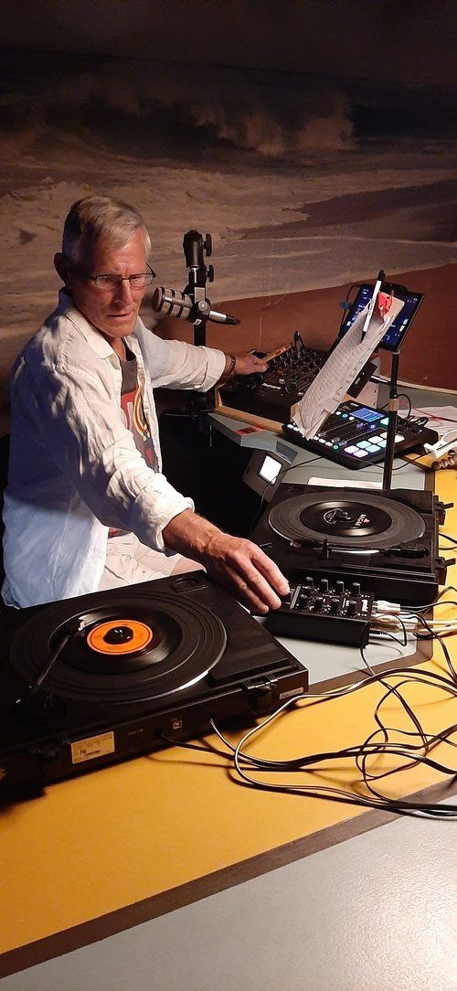 A man is sitting at a table playing music on a turntable.