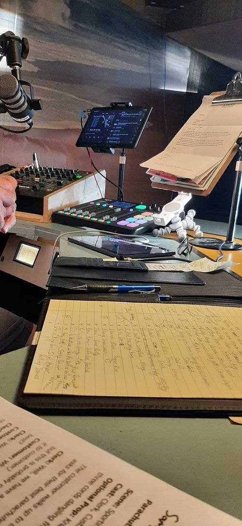 A person is sitting at a desk with a notebook and a remote control.