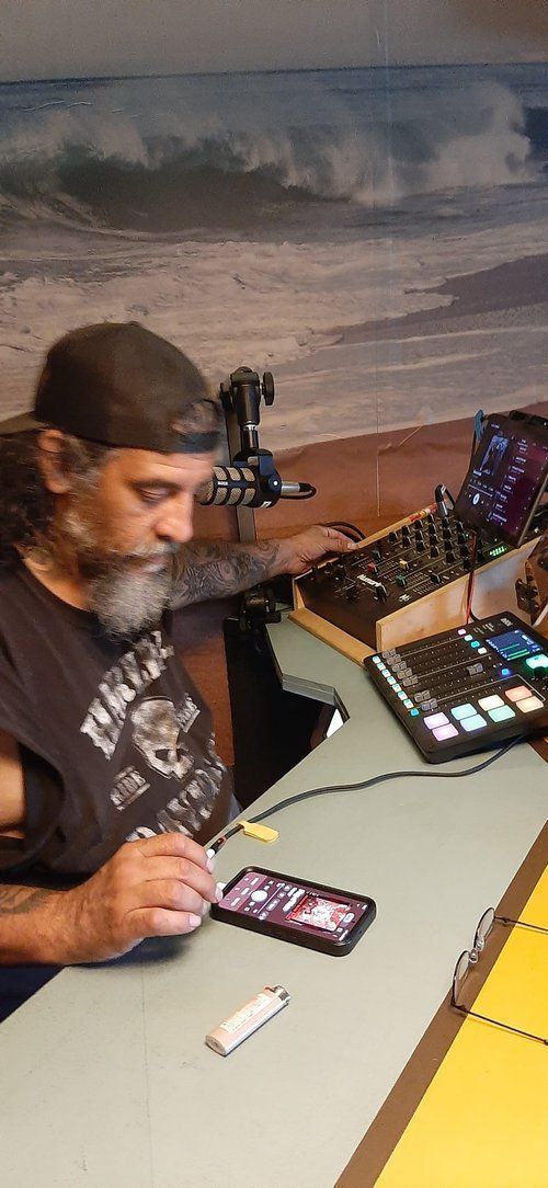 A man with a beard is sitting at a table looking at a cell phone.