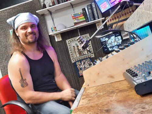 A man with a tattoo on his arm is sitting in a chair in front of a microphone.