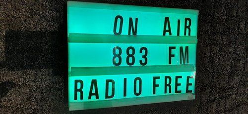 A sign that says on air 883 fm radio free