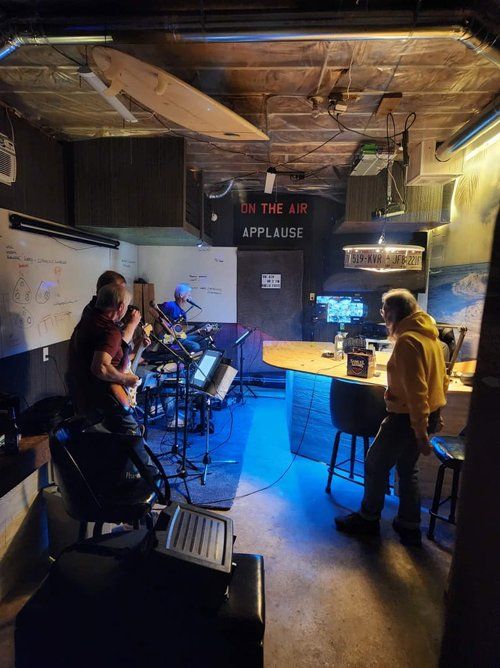 A group of people are playing instruments in a room with a sign that says applause