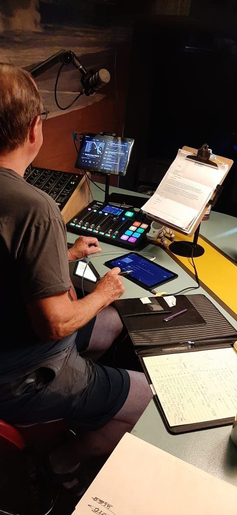 A man is sitting at a desk with a laptop and a tablet.