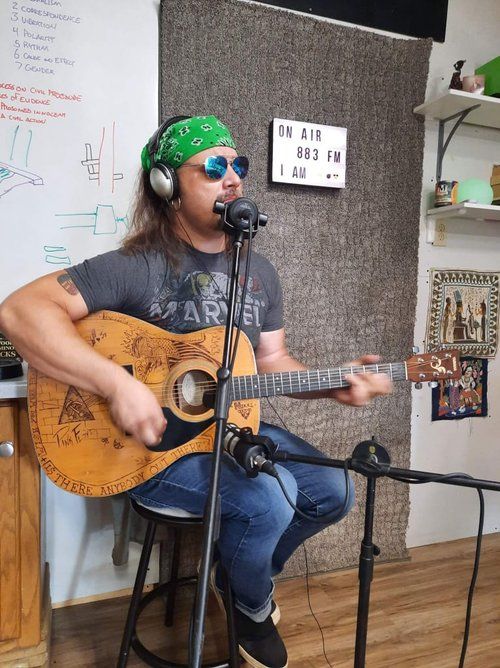 A man singing into a microphone while playing a guitar