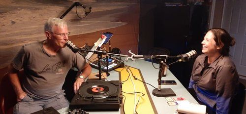 A man and a woman are sitting at a table in front of microphones.