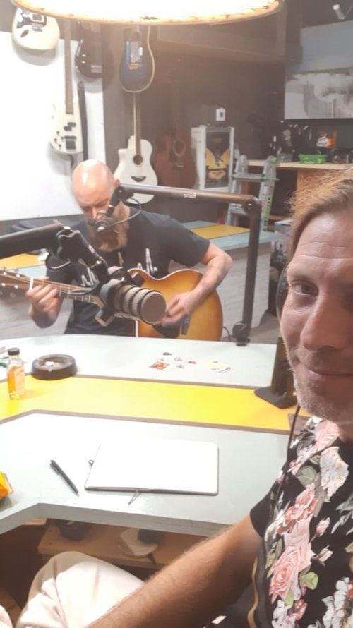 A man is playing a guitar while another man takes a picture