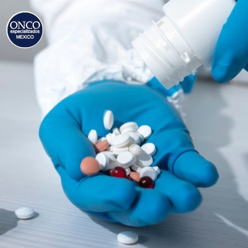Manos con guantes sosteniendo pastillas y cápsulas.