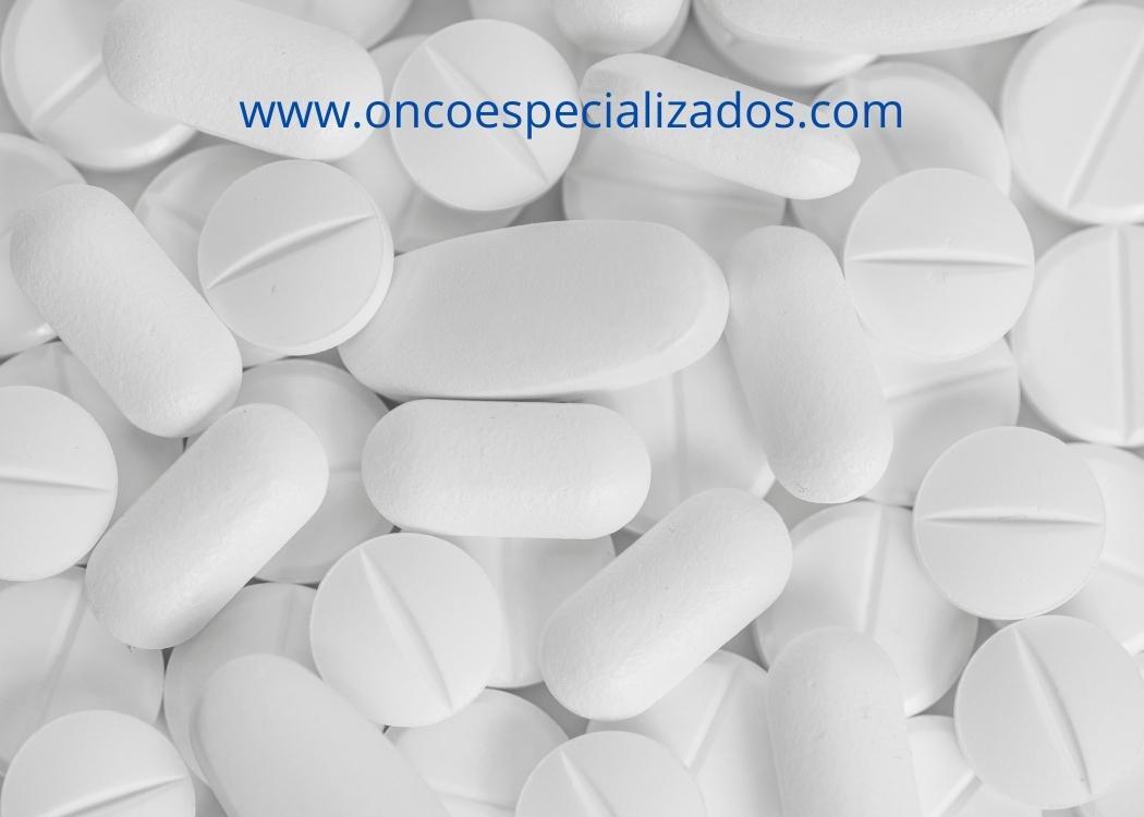 Un montón de pastillas blancas capecitabina con la página web www.oncoespecializados.com en la parte inferior