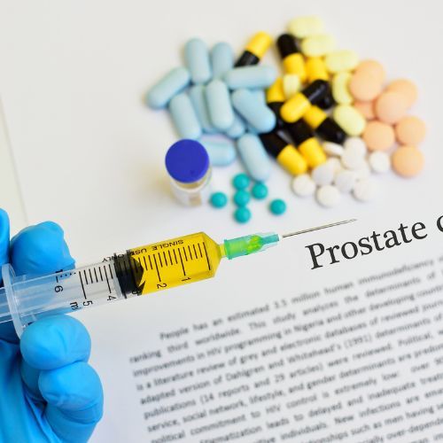 Una persona sostiene una jeringa frente a un papel que dice cáncer de próstata.