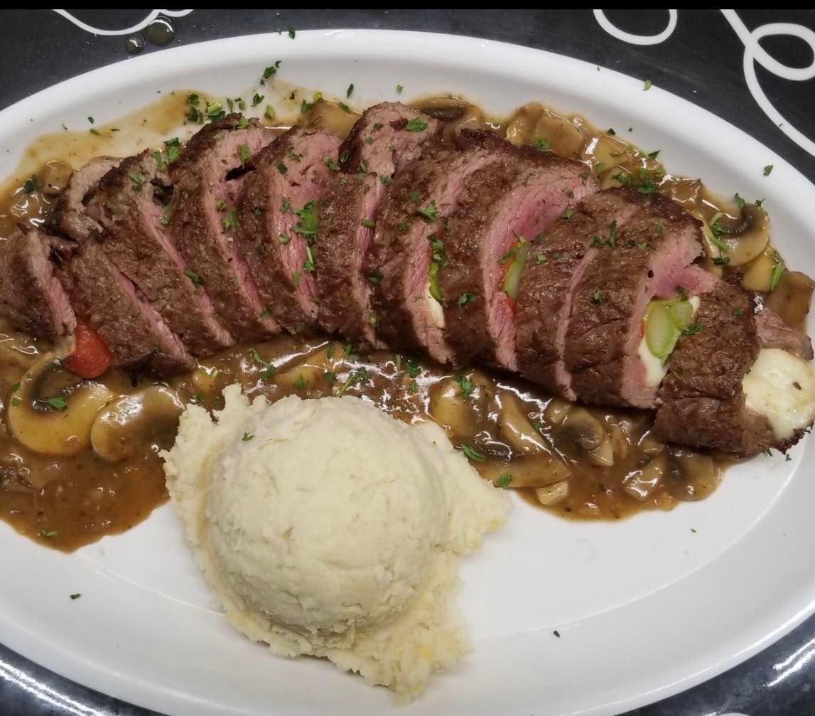 A white plate topped with meat and mashed potatoes