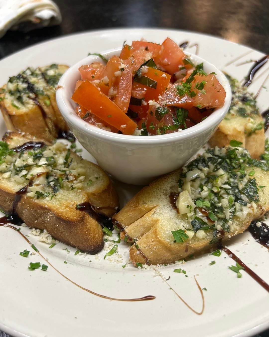 A white plate topped with bread and a bowl of tomato sauce.