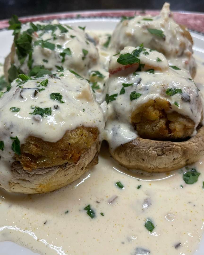 A close up of a plate of food with mushrooms and sauce on a table.