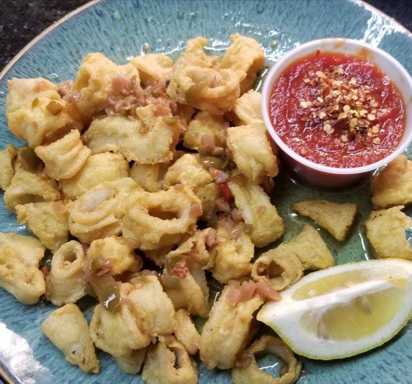 A plate of food with a cup of sauce and a slice of lemon