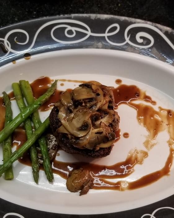 A white plate with a steak and green beans on it