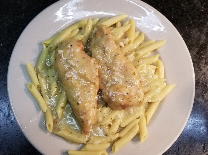 A white plate topped with pasta and chicken on a table