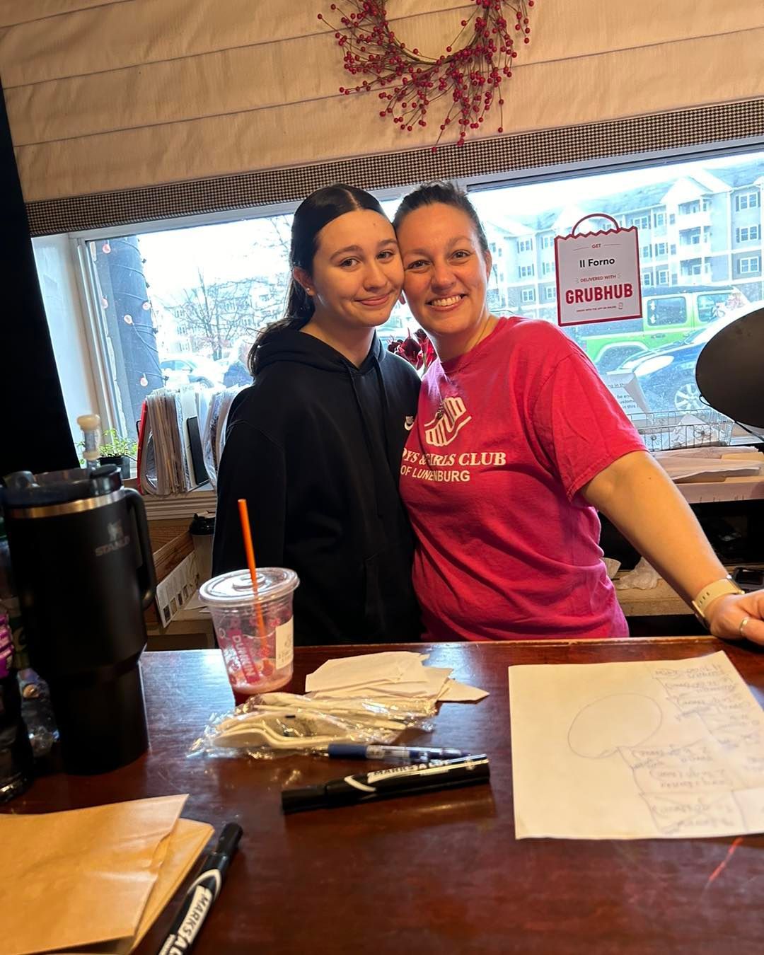 Two women standing at a counter with a sign that says donuts on it
