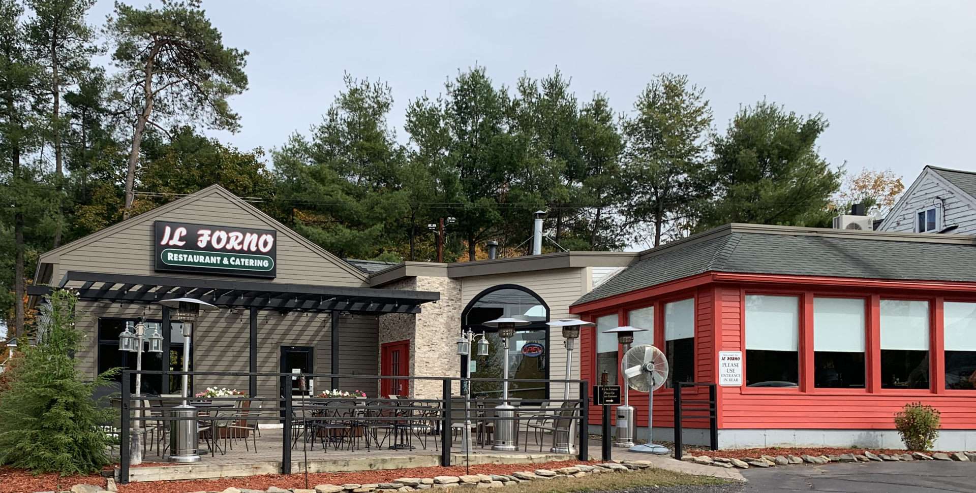 A restaurant with a red building and a patio in front of it.