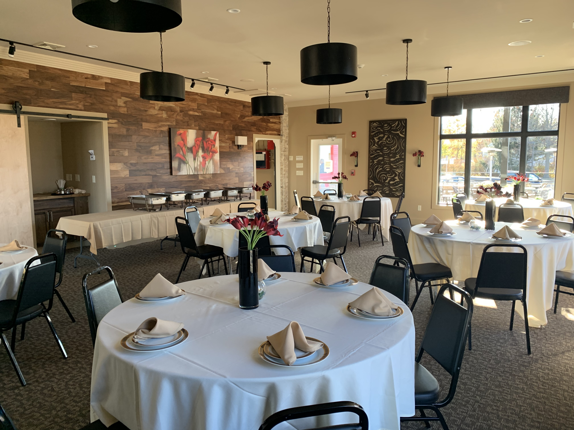 A large room with tables and chairs set up for a wedding reception.