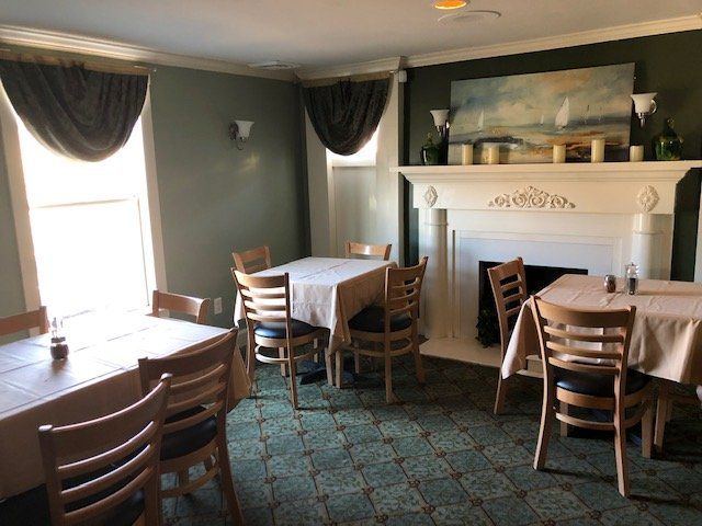 A dining room with tables and chairs and a fireplace.