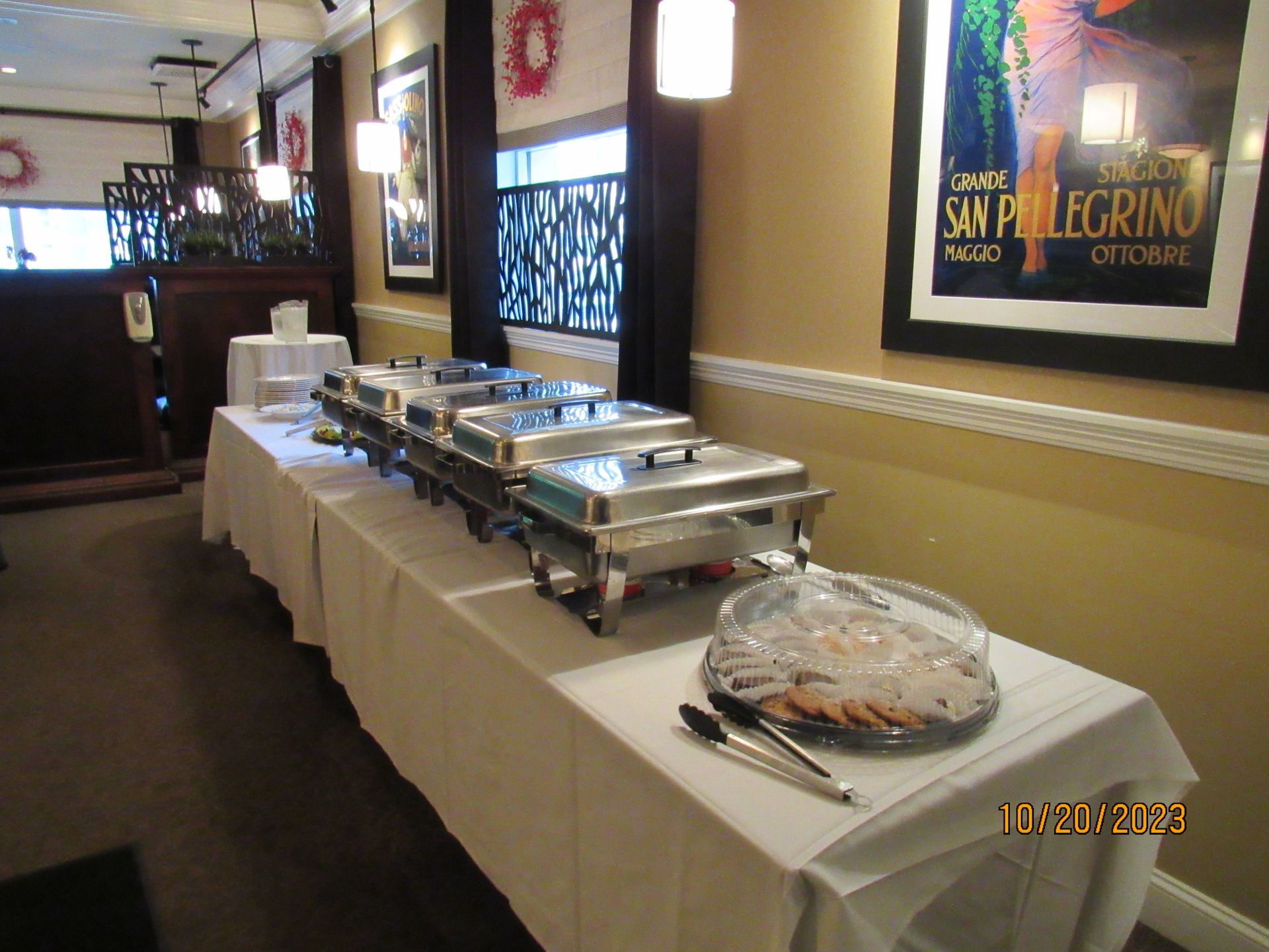 A buffet line in a restaurant with a poster on the wall that says san pellegrino