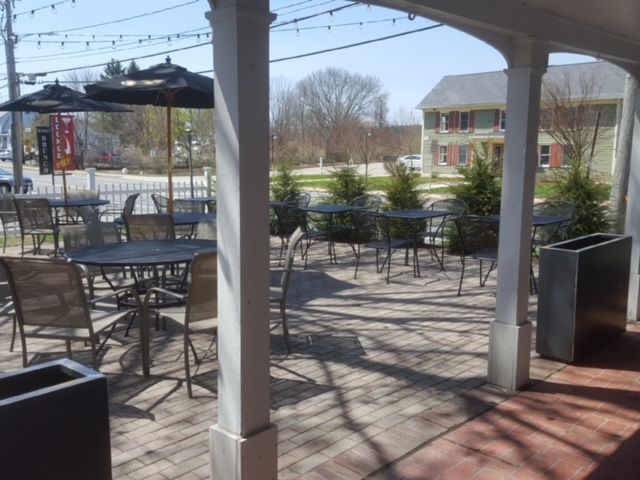 A patio with tables and chairs and umbrellas on a sunny day