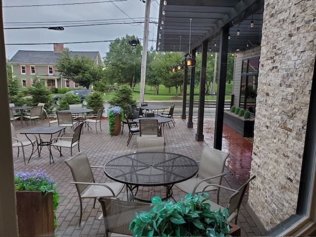 A view of a patio with tables and chairs from a window.