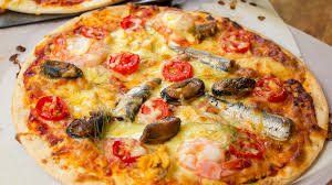 Pizza topped with shrimp, mussels, sardines, and tomatoes.