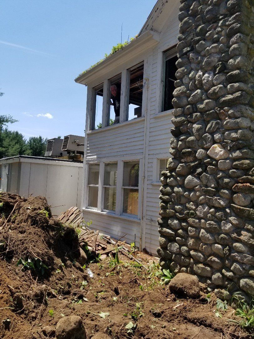 A white house with a stone chimney is being demolished.