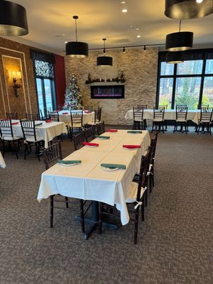 A large dining room with tables and chairs and a fireplace.