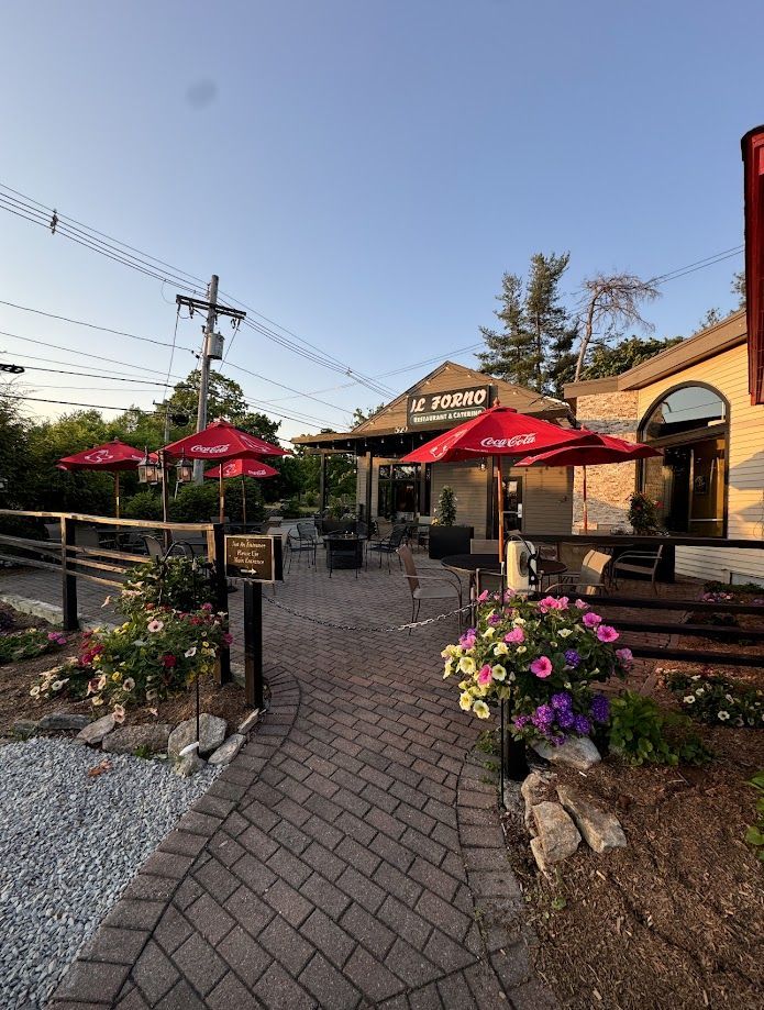 A brick walkway leading to a restaurant with red umbrellas