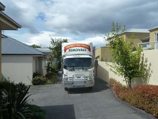 Workers carrying wrapped furniture during an indoor removal or moving process.
