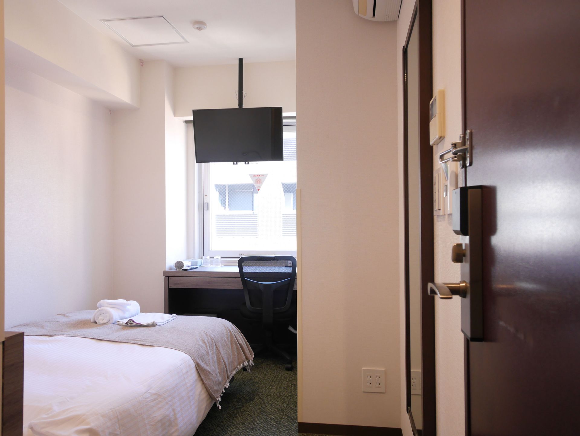 Compact hotel room with bed and nightstand in Ginza