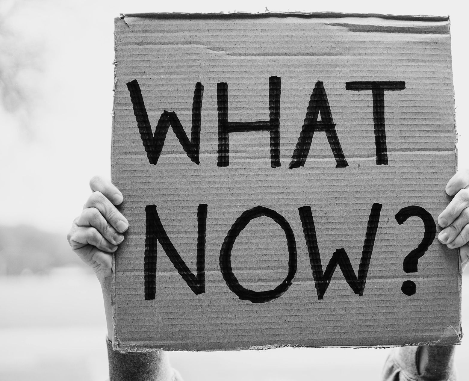 A person holds a cardboard sign with the question 